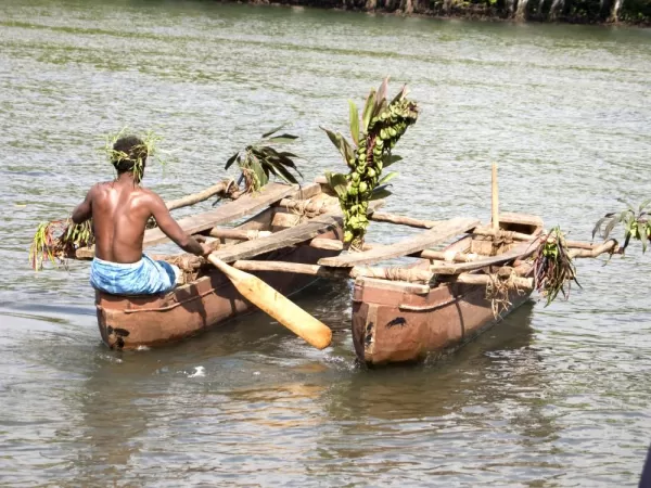 A tribal man pushing two canoes