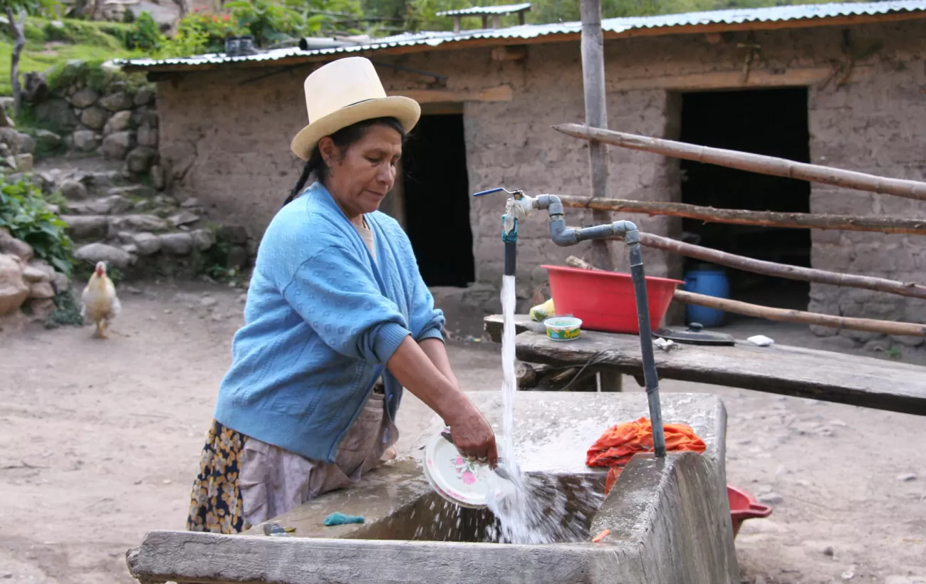 A Quechua woman washes dishes in her courtyard along the Inca Trail