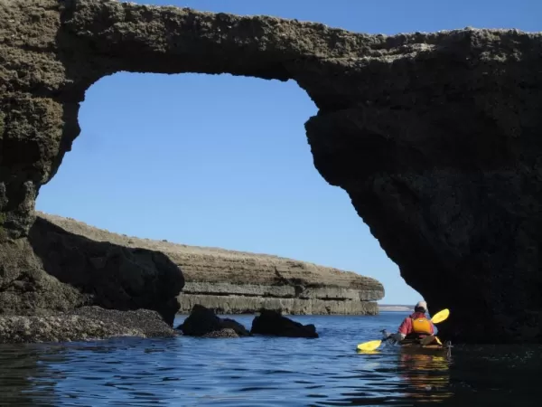 Kayaking through an ocean-eroded rock archway on the Peninsula Valdes
