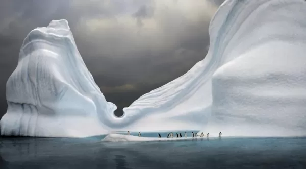 Penguins sit at the base of this beautiful iceberg.