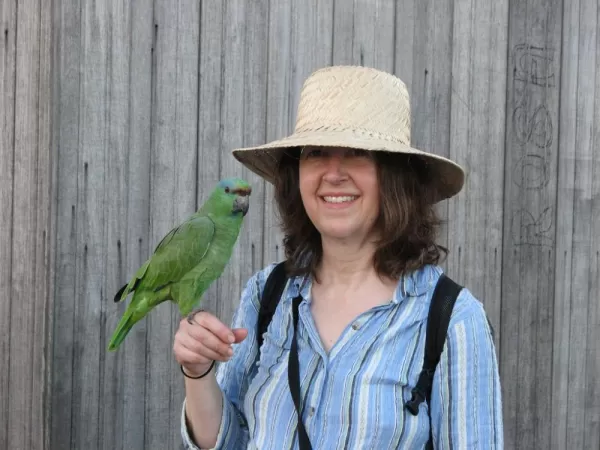 A traveler makes friends with a parrot.