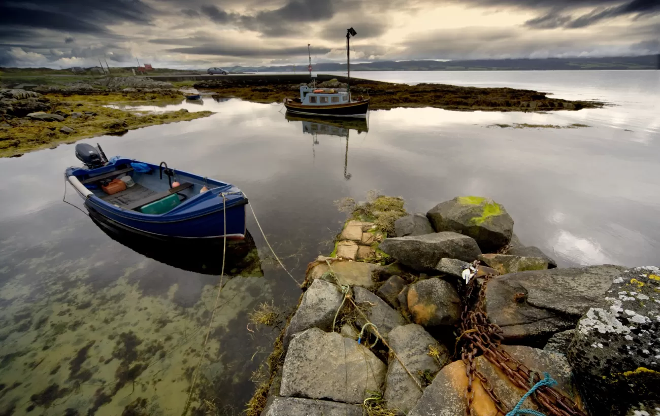 Two boats sit on the coast during an overcast day.