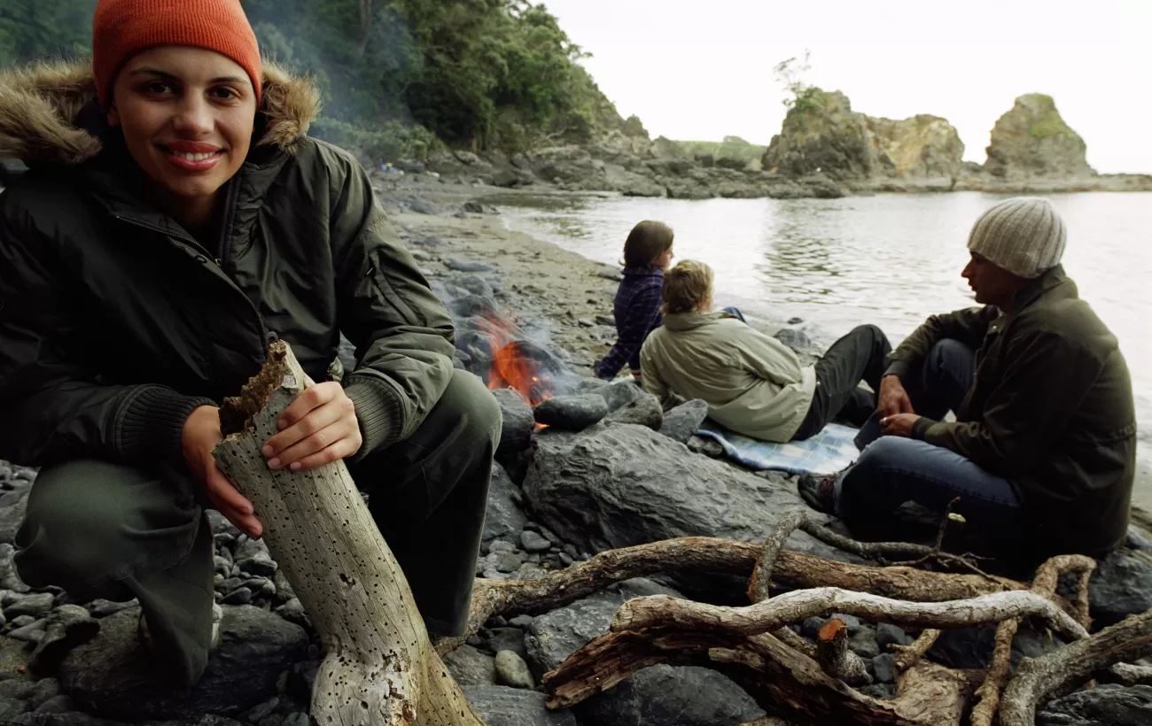 A group fo people enjoying a fire on the coast of New Zealand.