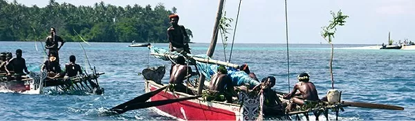 Traditional fishing boats sail the waters off the coast of New Guinea