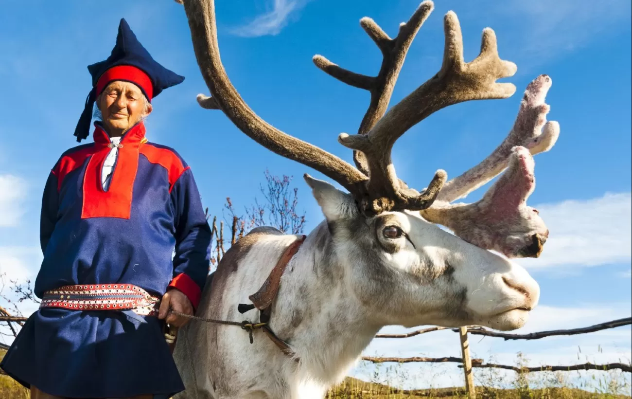 A local man in traditional norwegian dress and his reindeer